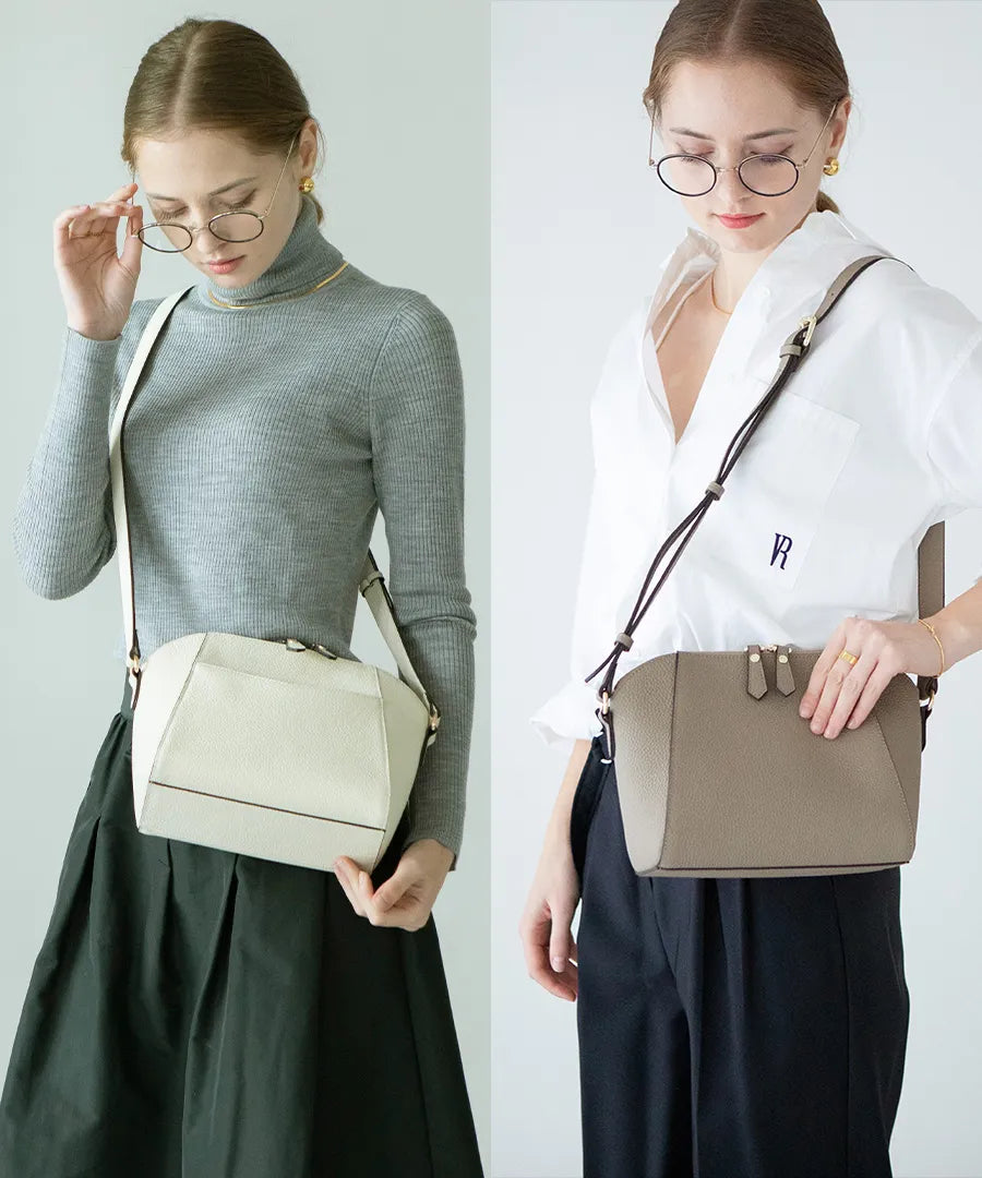 A female model is carrying a shoulder bag "Herena" over her shoulder. Color: Greige,Ivory