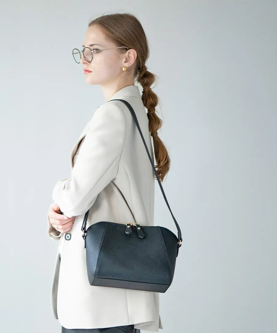 A female model is carrying a shoulder bag "Herena" over her shoulder. Color:Black