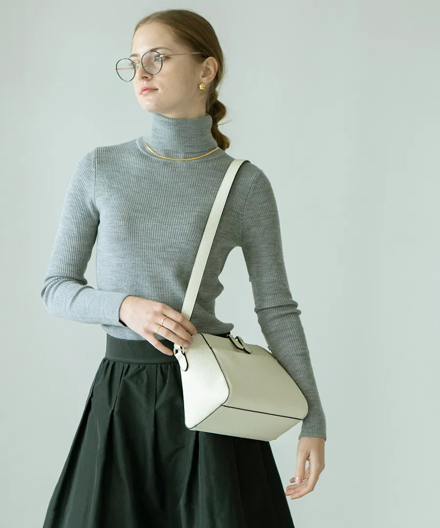 A female model is carrying a shoulder bag "Herena" over her shoulder. Color:Ivory