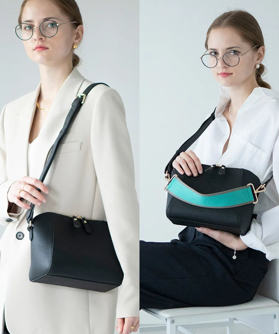 A female model is carrying a shoulder bag "Herena" over her shoulder. Color:Black