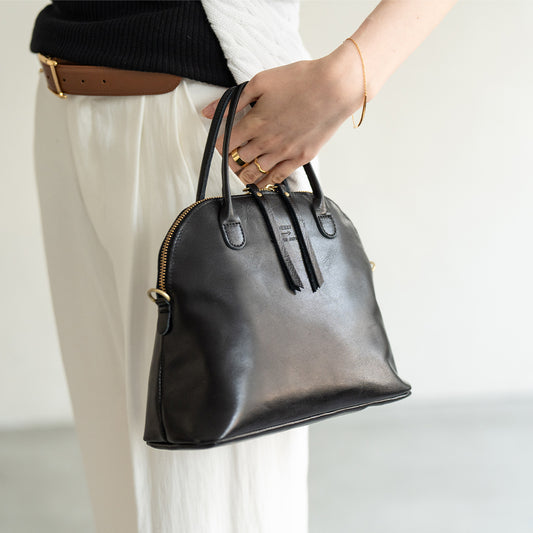 A woman has a bag (color: black) in her hand