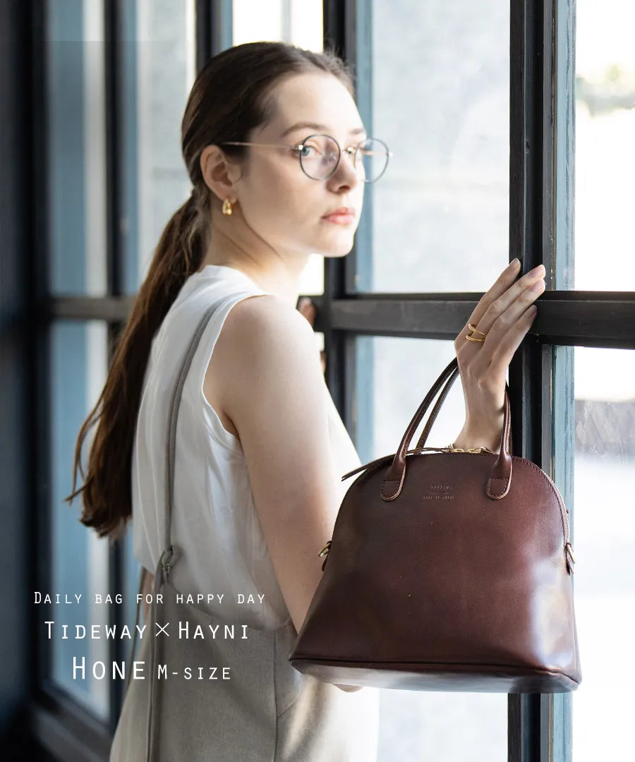 A woman has a bag (color: chocolate brown) in her hand