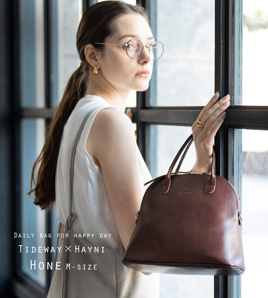 A woman has a bag (color: chocolate brown) in her hand