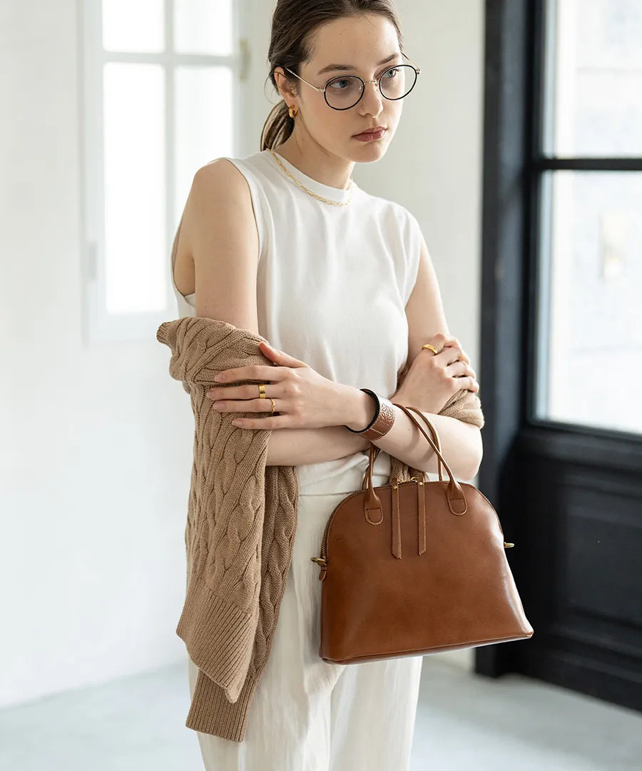 A woman has a bag (color: camel brown) in her hand