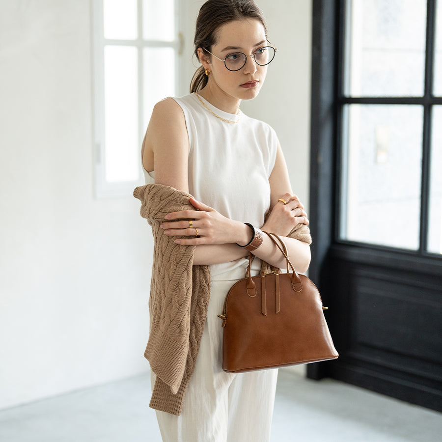 A woman has a bag (color: camel brown) in her hand