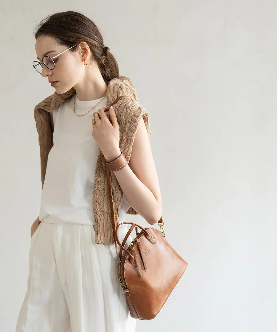 A woman is wearing a bag (color: camel brown) over her shoulder