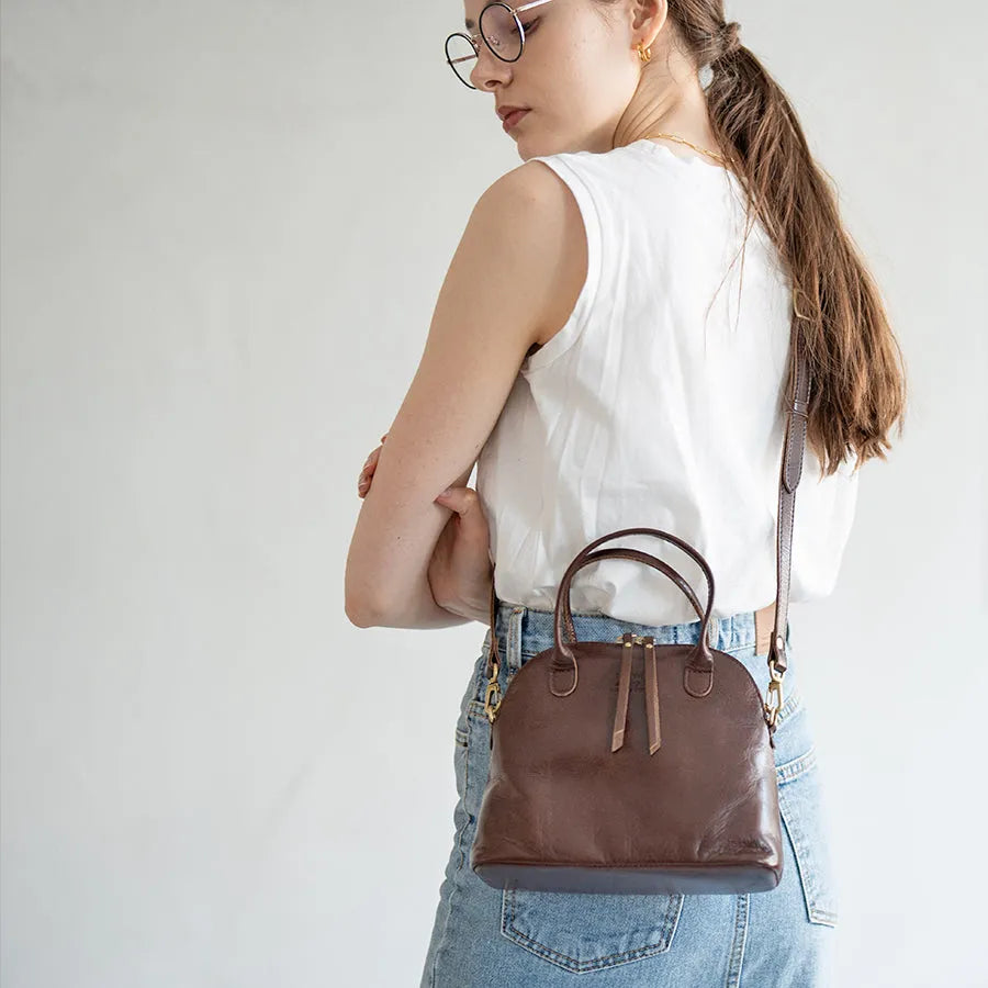 A female model is carrying a shoulder bag "Hone S-size (Version 2)" over her shoulder. Color:Chocolate brown