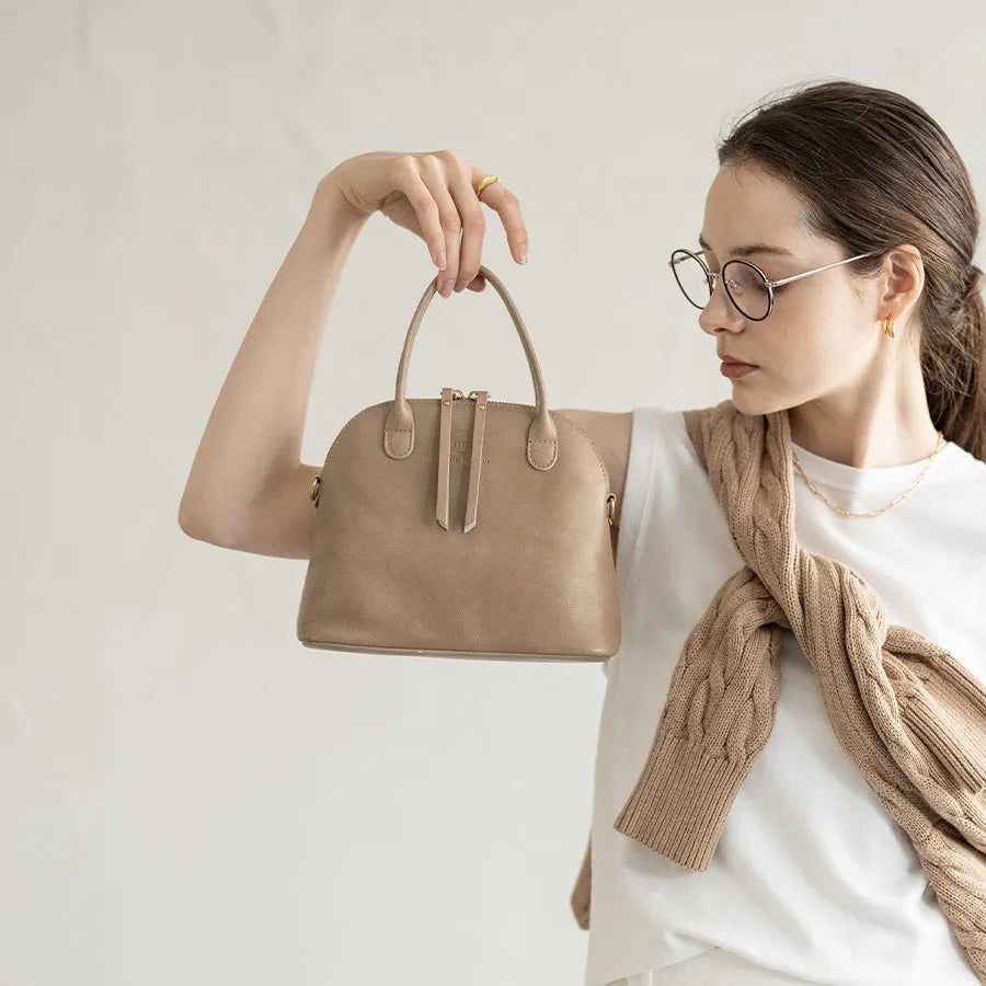 A female model is holding a tote bag "Hone S-size (Version 2)" Color:Sand greige