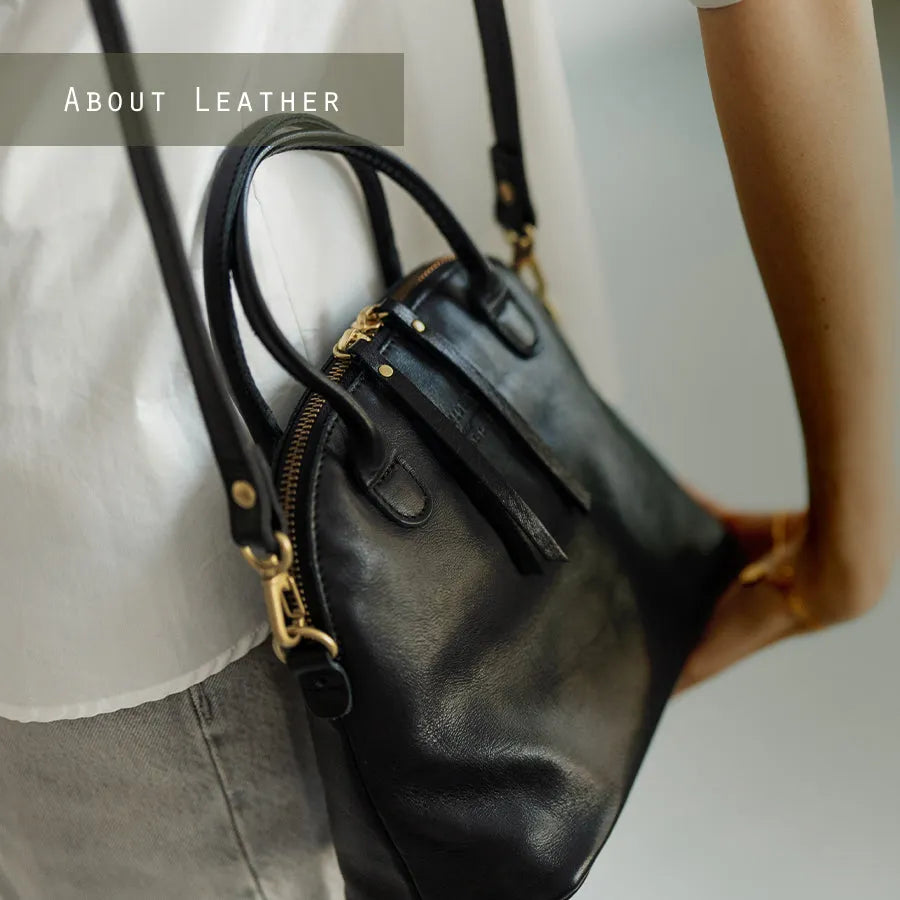 A female model is carrying a shoulder bag "Hone S-size (Version 2)" over her shoulder. Color:Black