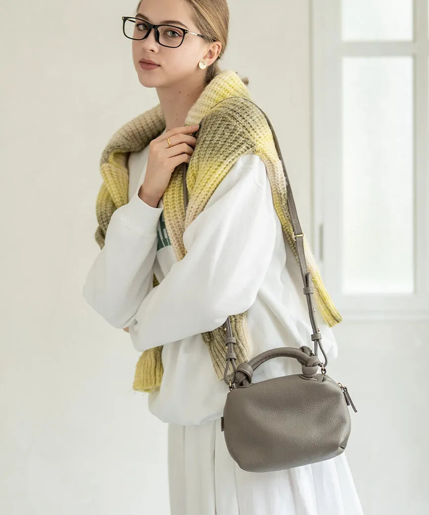 A female model is carrying a shoulder bag "Leatherpom S" over her shoulder. Color:Gray