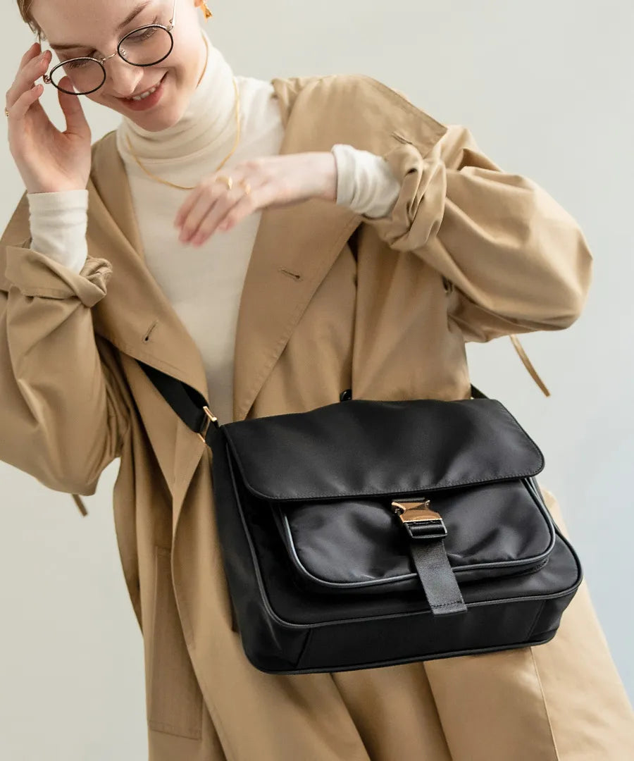 A female model is carrying a shoulder bag “Lenum” over her shoulder. Color:Black