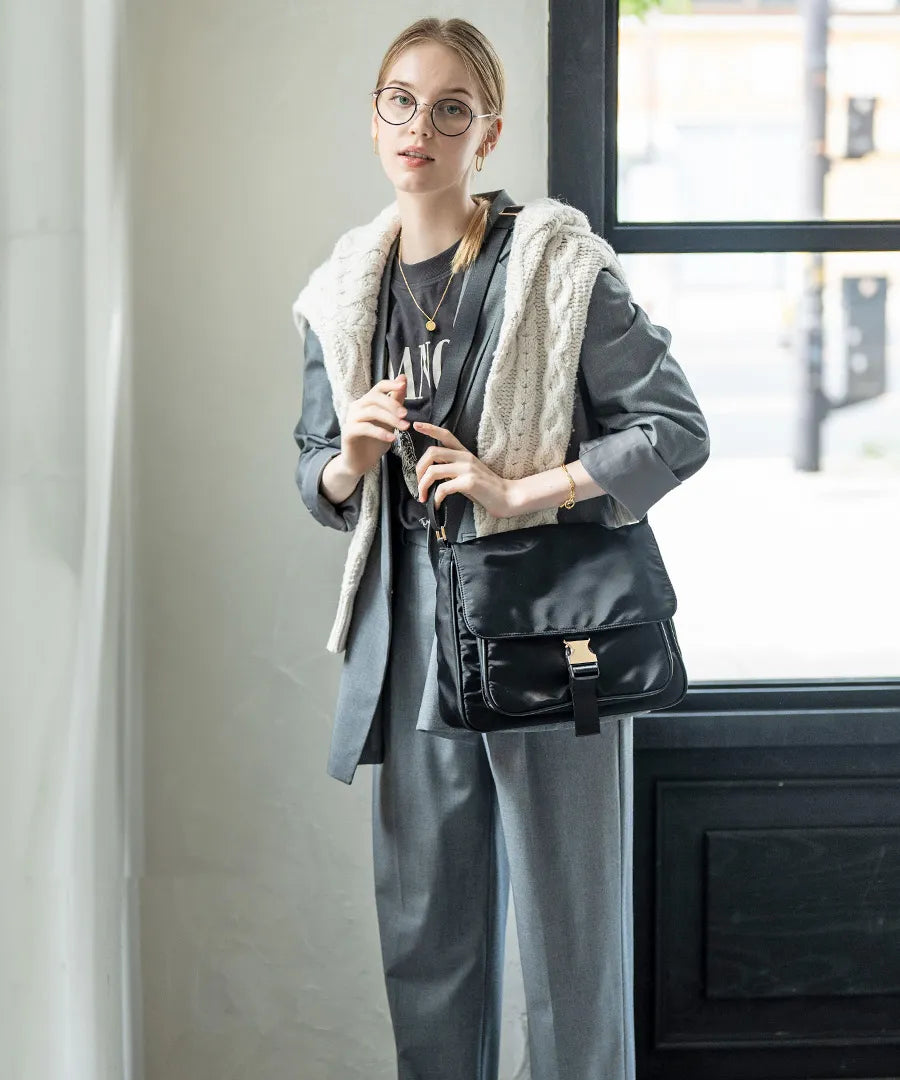 A female model is carrying a shoulder bag “Lenum” over her shoulder. Color:Black