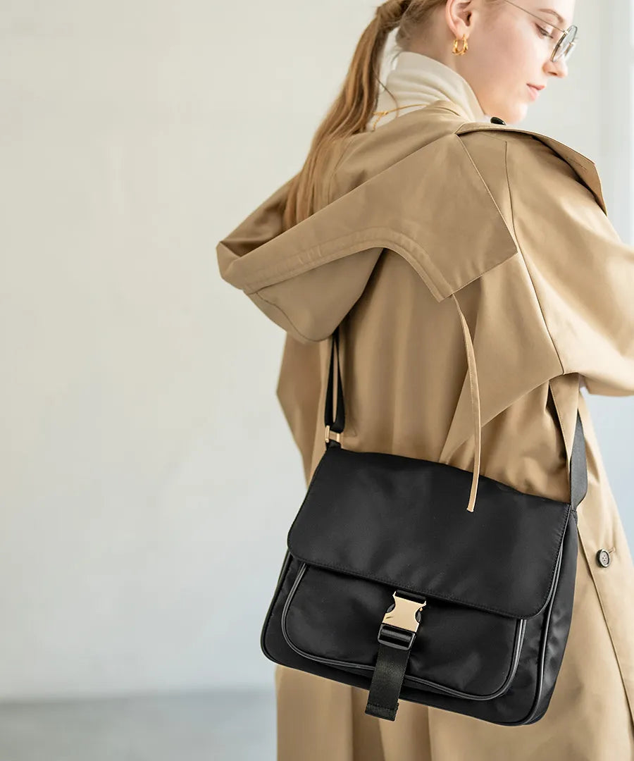 A female model is carrying a shoulder bag “Lenum” over her shoulder. Color:Black