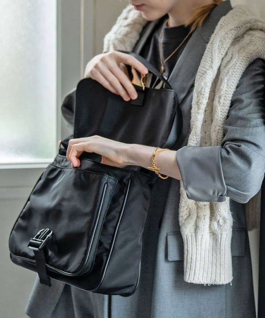 A female model is carrying a shoulder bag “Lenum” over her shoulder. Color:Black