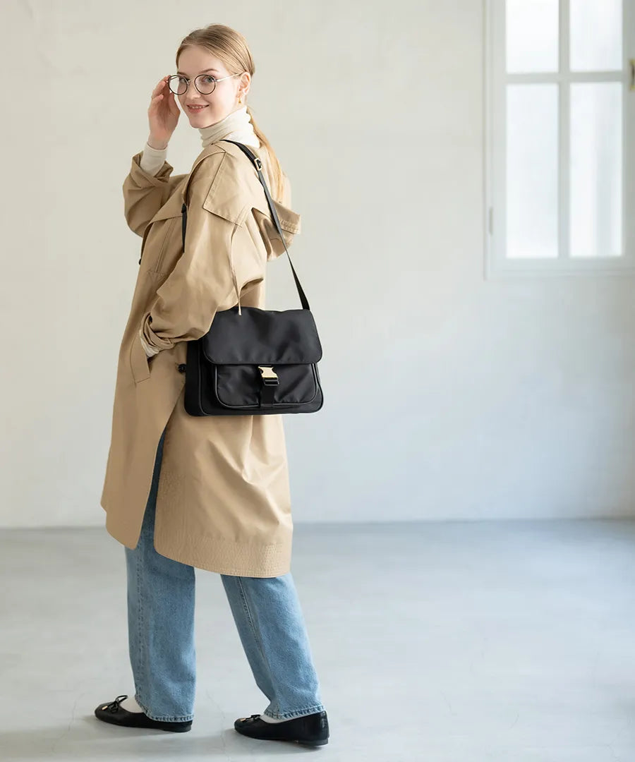 A female model is carrying a shoulder bag “Lenum” over her shoulder. Color:Black