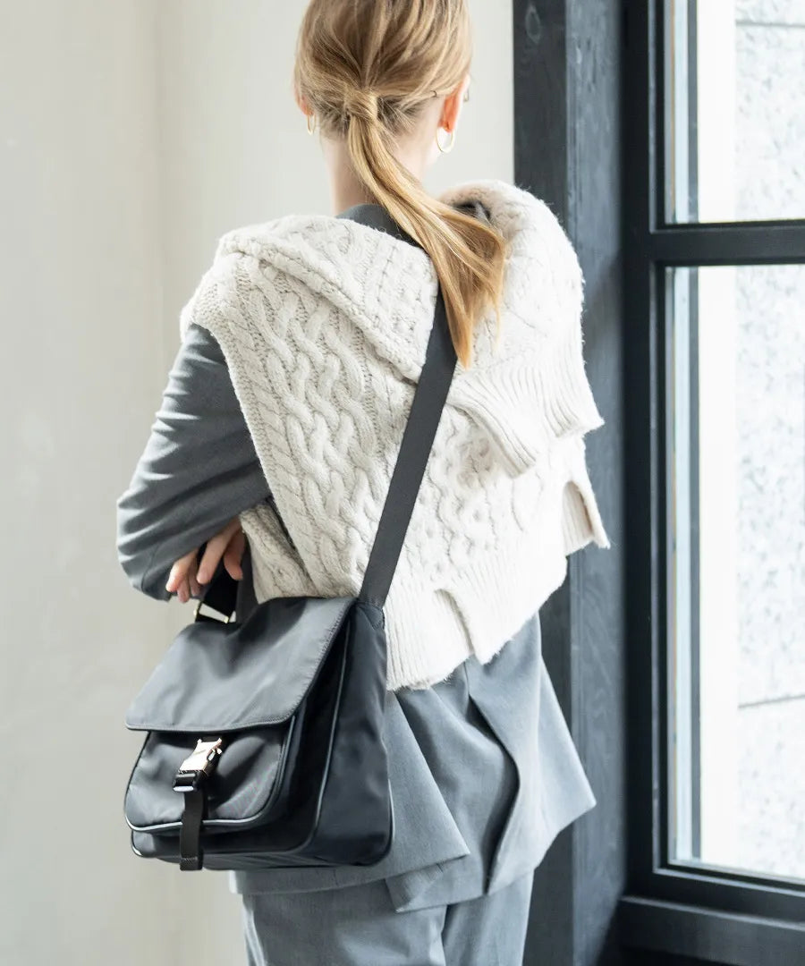 A female model is carrying a shoulder bag “Lenum” over her shoulder. Color:Black