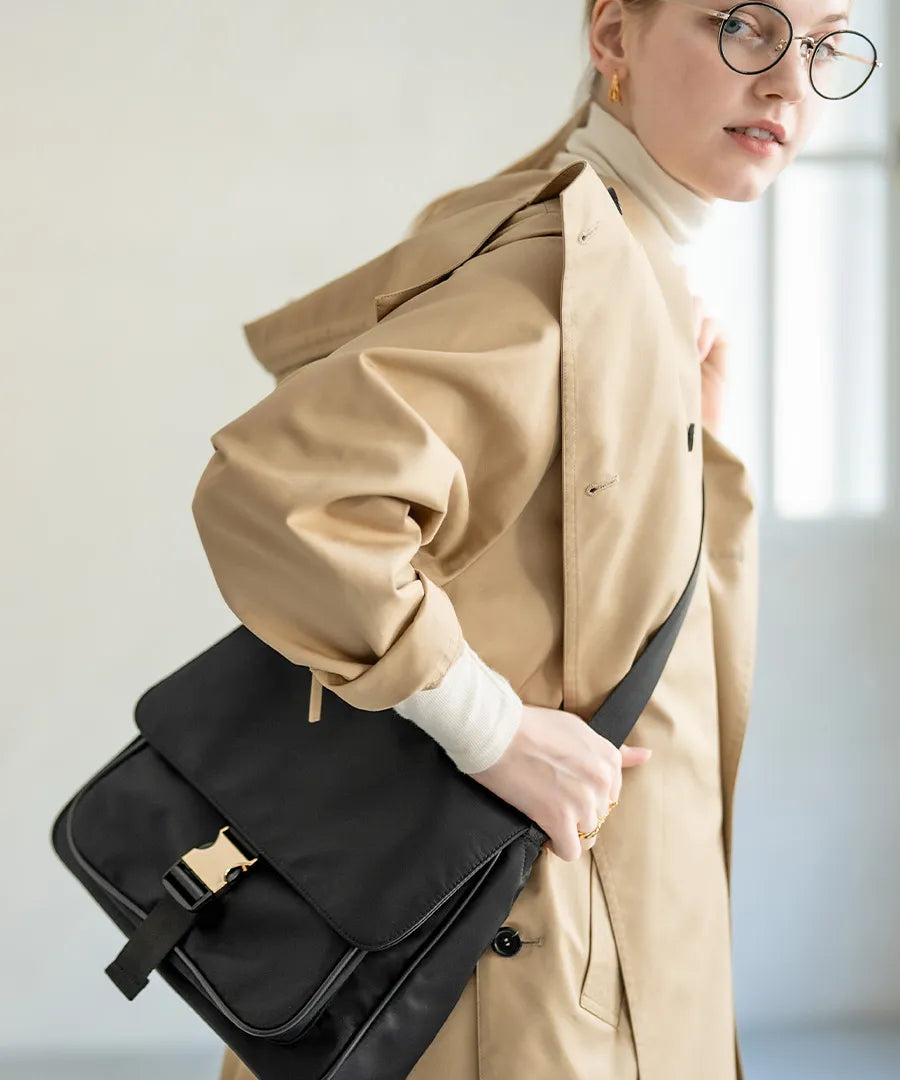 A female model is carrying a shoulder bag “Lenum” over her shoulder. Color:Black