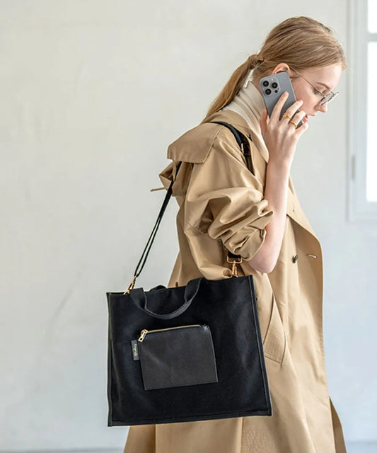 A female model is carrying a shoulder bag “Lesche” over her shoulder. Color:Black