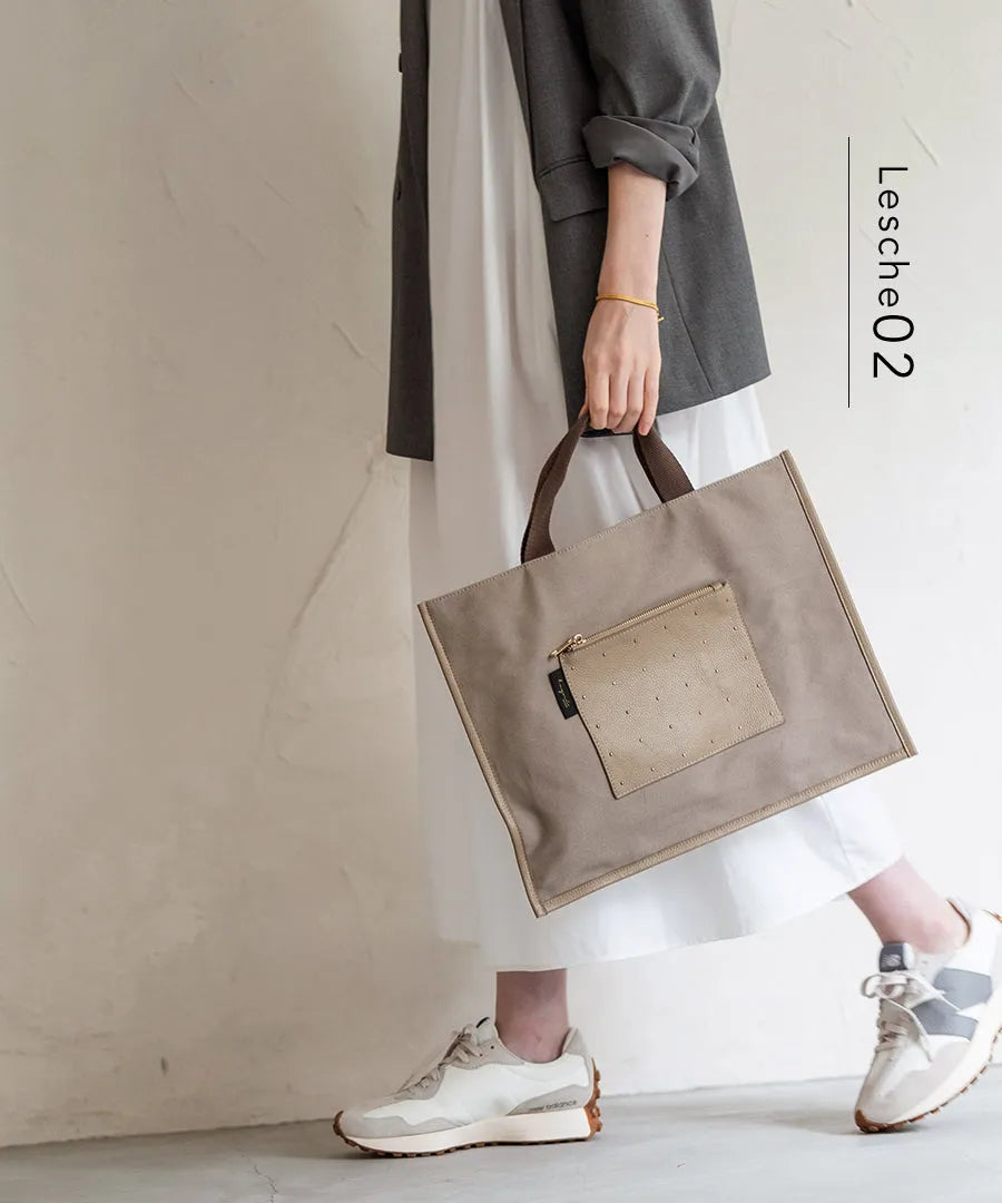 A female model is carrying a tote bag “Lesche”. Color:Dots greige