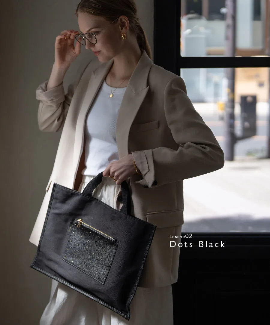 A female model is carrying a tote bag “Lesche”. Color:Dots black