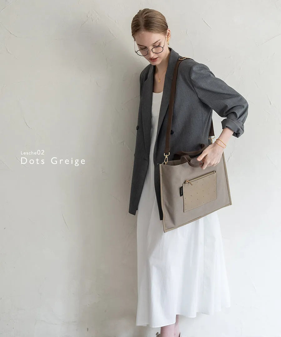 A female model is carrying a shoulder bag “Lesche” over her shoulder. Color: Dots greige