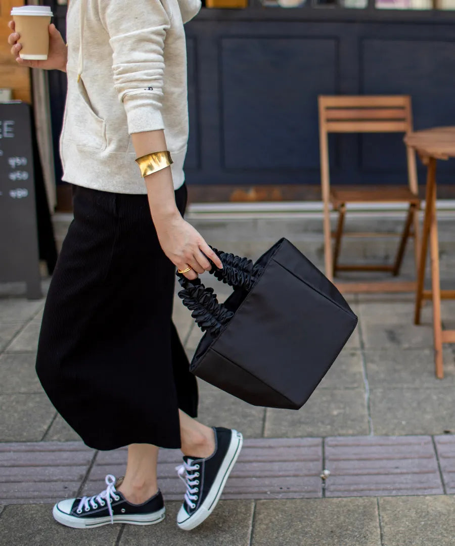 A female model is carrying a tote bag “lifuka nylon S” Color: Black