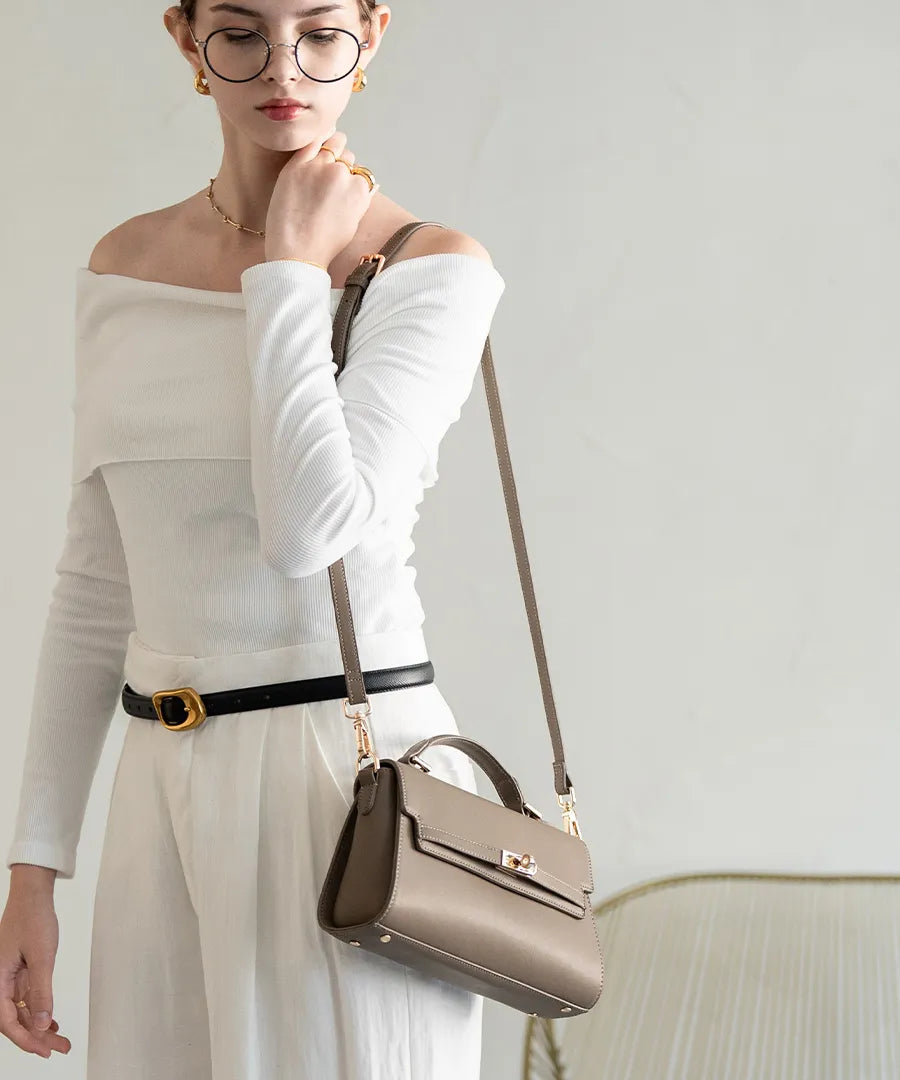 A female model is carrying a shoulder bag "Linzy" over her shoulder. Color:Taupe