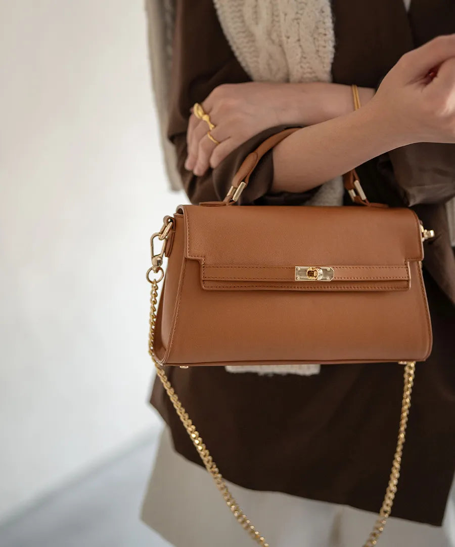 A female model is holding a hand bag "Linzy". Color: Camel
