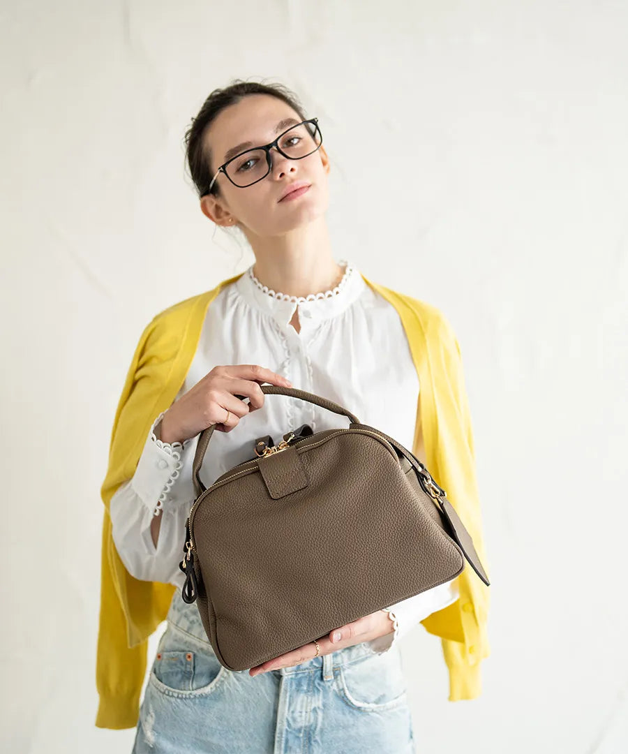 A female model is holding a tote bag "Mini Loche (Version 7)".Color:Taupe