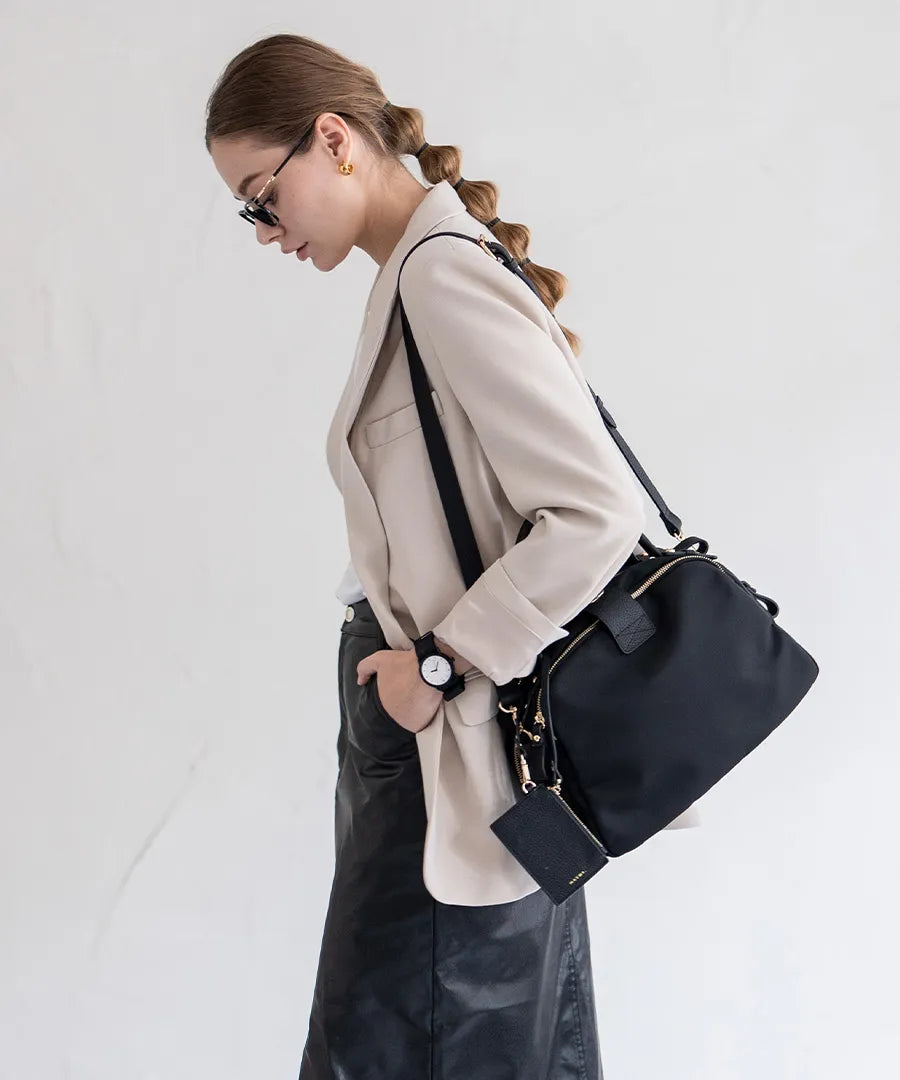 A female model is carrying a body bag "Mini Nylon Loche" over her shoulder.Color:Black