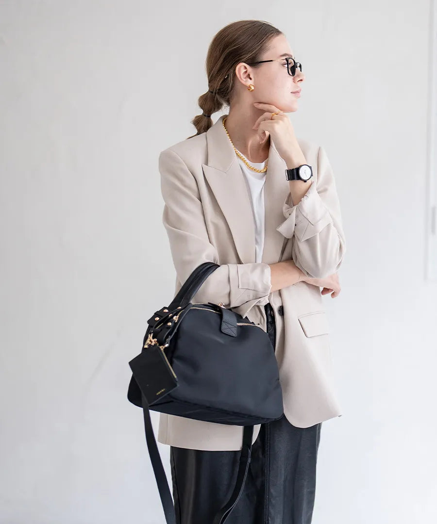 A female model is holding a hand bag "Mini Nylon Loche".Color:Black