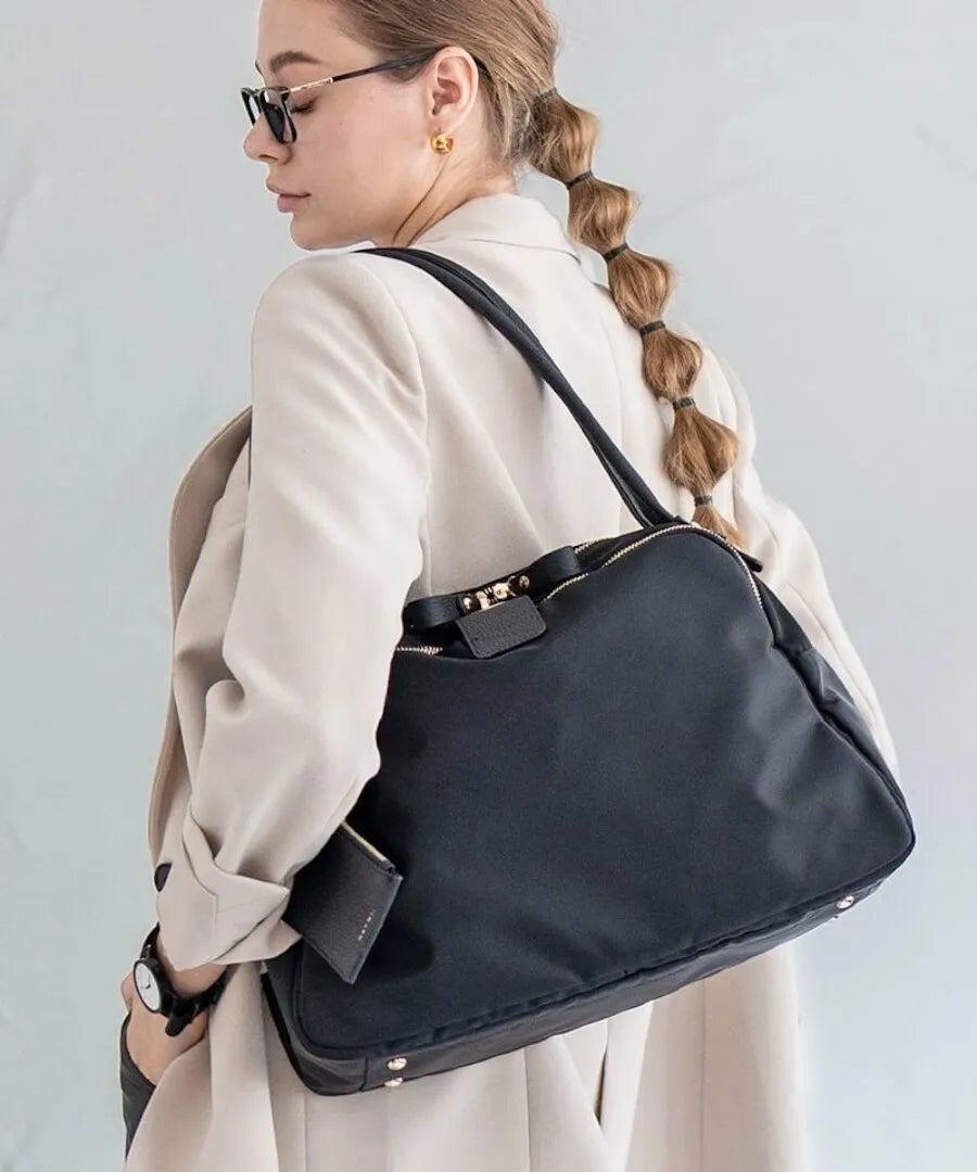 A female model is holding a tote bag "Nylon Loche L (Long Handle)".Color:Gray Black