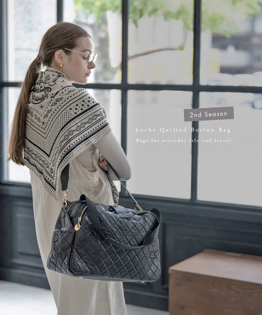 A female model is carrying a shoulder bag "Loche Quilted Boston Bag" over her shoulder.