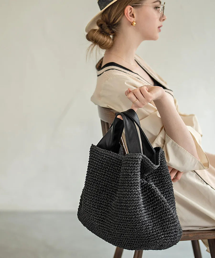 A female model is sitting and holding a hand bag "Najia".