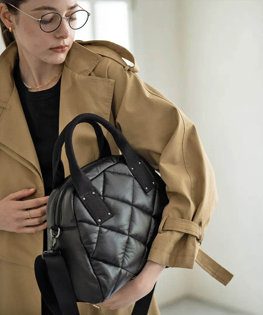 A female model is holding a tote bag "Peremo (Version 2)".Color:Black