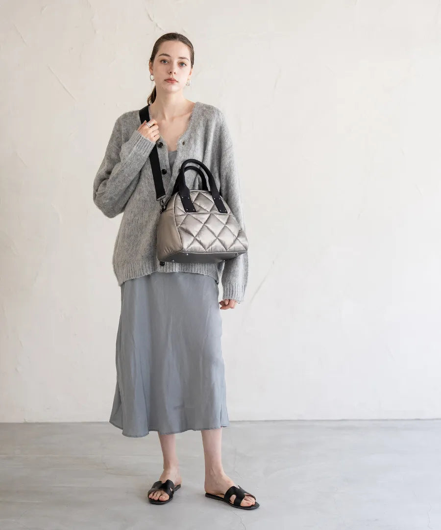 A female model is carrying a tote bag "Peremo (Version 2)" over her shoulder.Color:Champagne silver