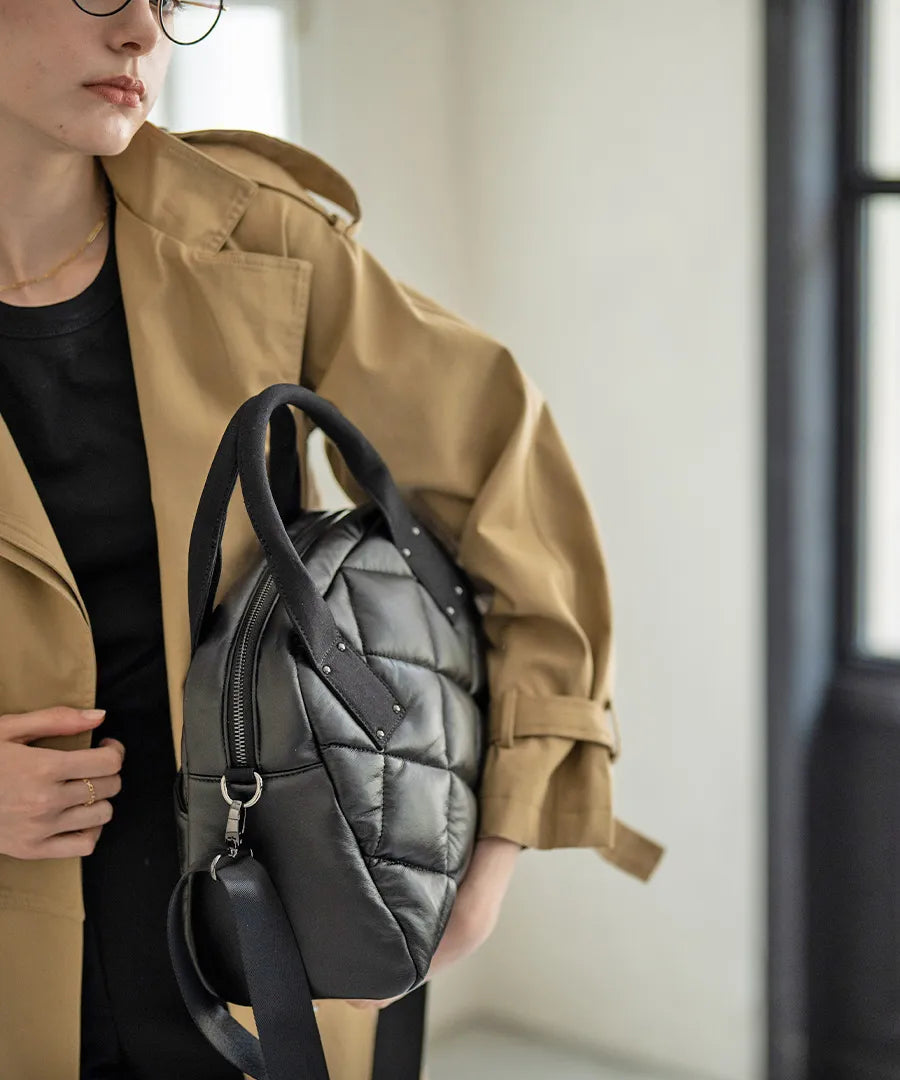 A female model is holding a tote bag "Peremo (Version 2)".Color:Black