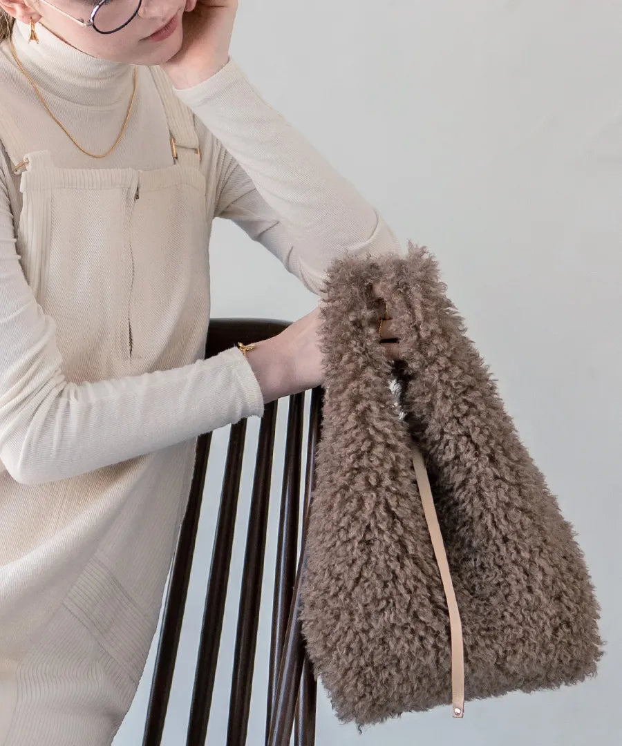 A female model is holding a fur tote bag "Pudle" Color:Mocha brown