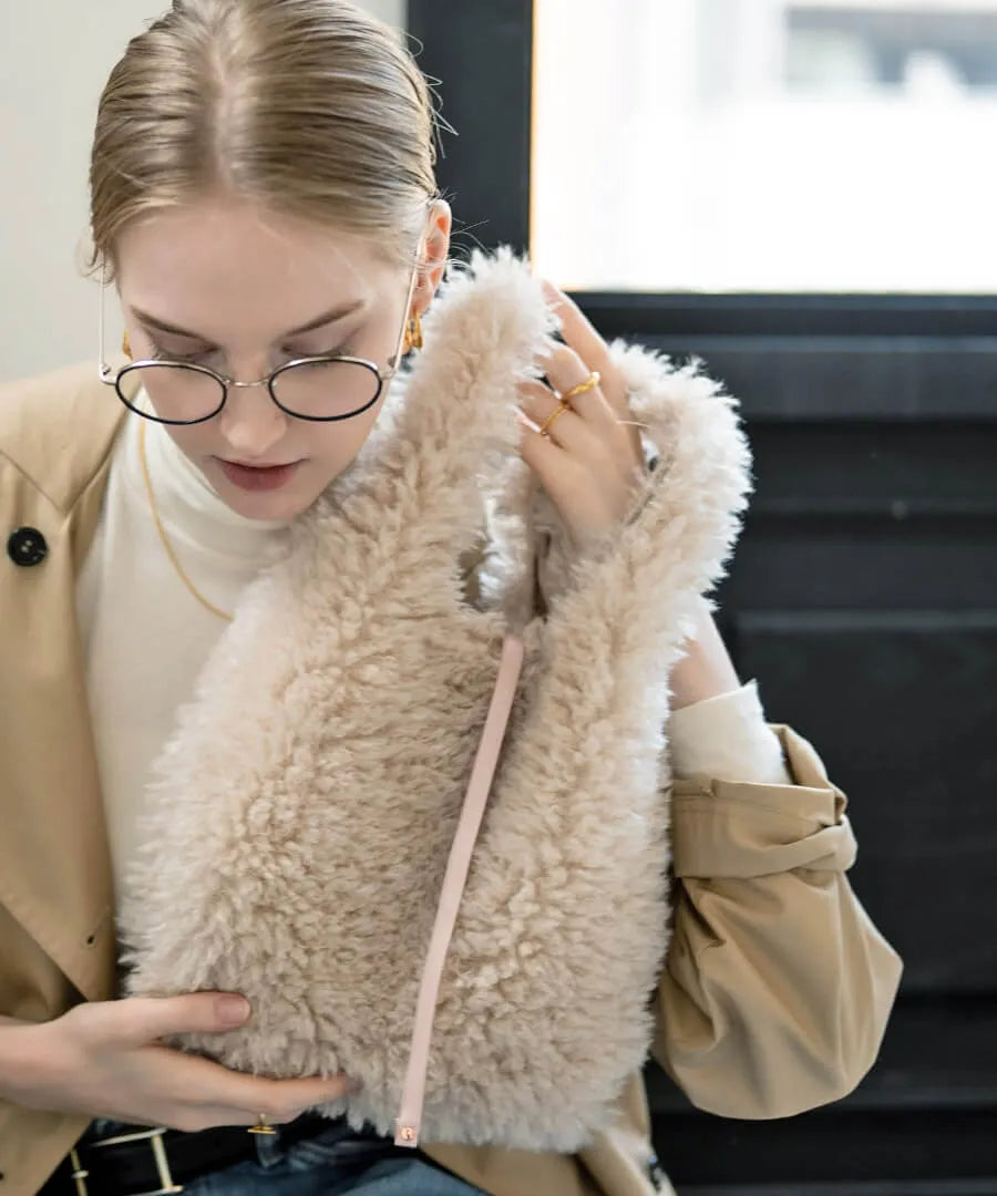 A female model is holding a fur tote bag "Pudle" Color:Ivory