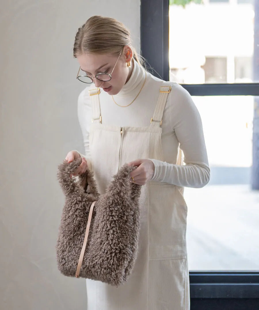 A female model is holding a fur tote bag "Pudle" Color:Mocha brown