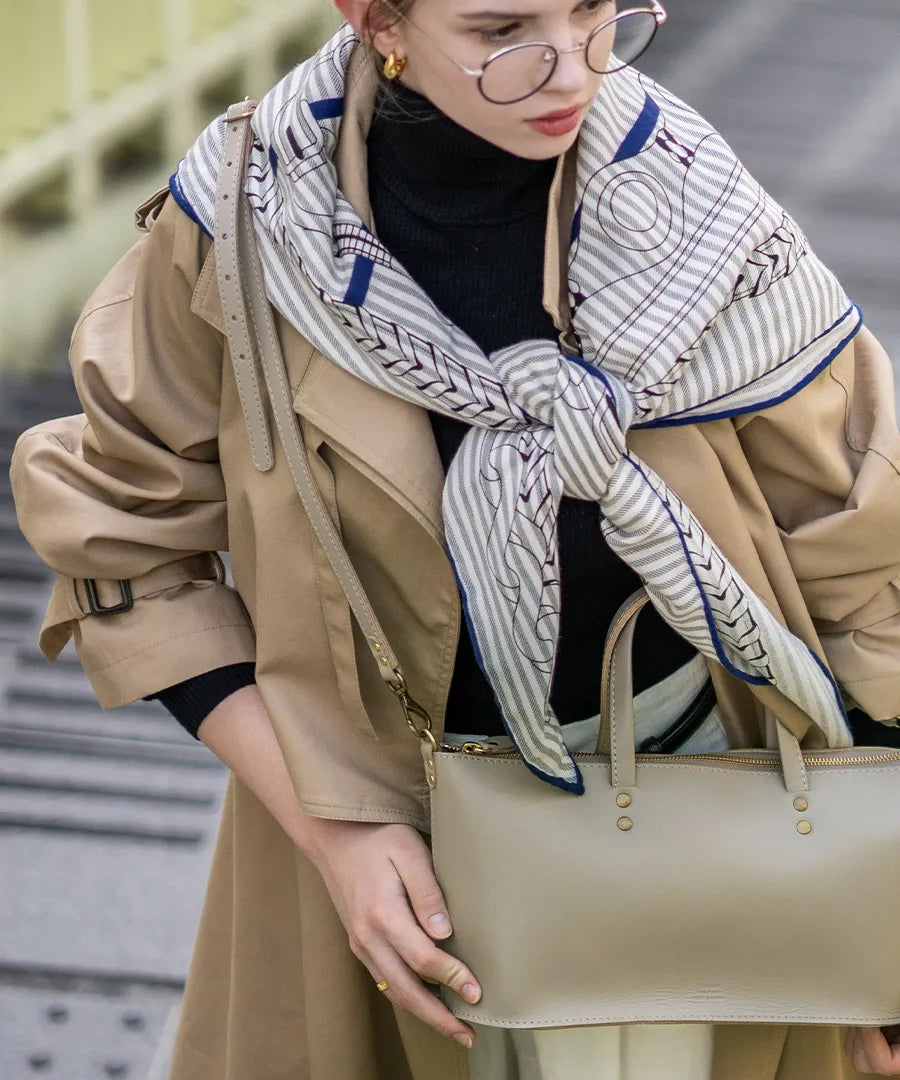 A female model is carrying a shoulder bag "Recte" over her shoulder. Color:Greige