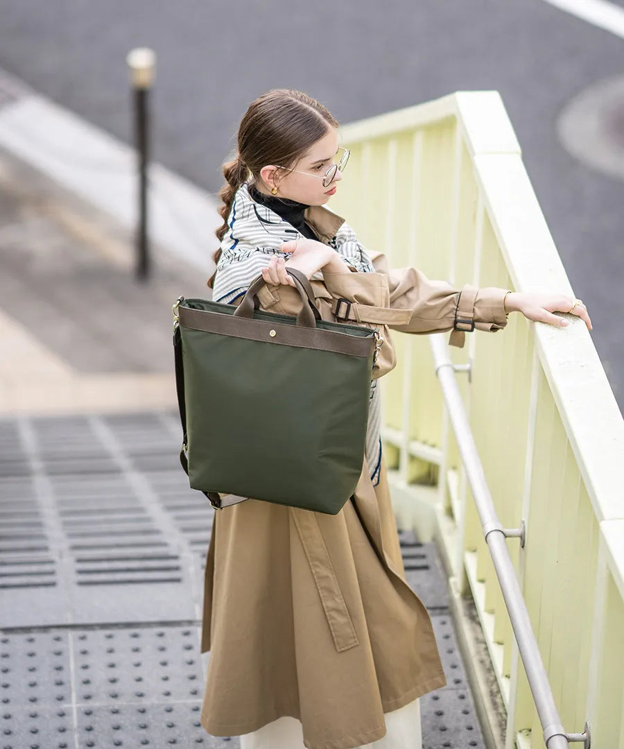 A female model is holding a tote bag "Serem". Color: Khaki