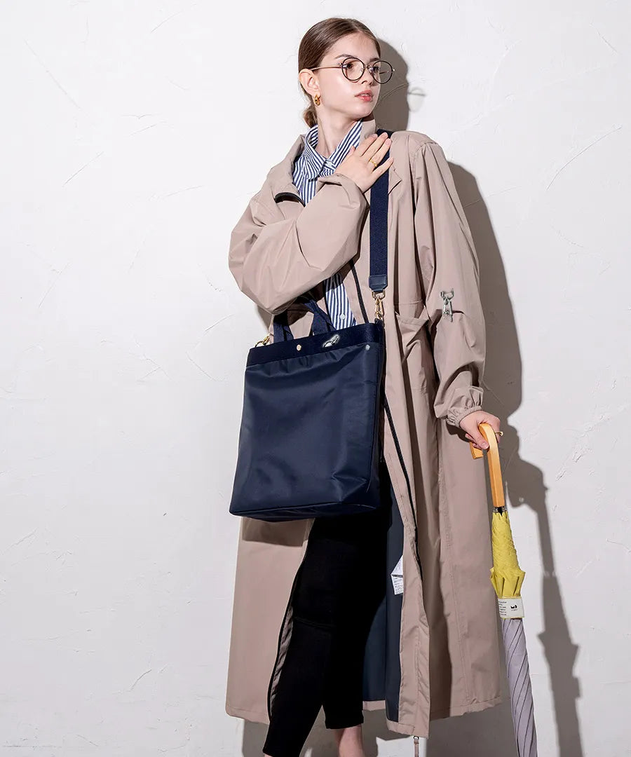 A female model is carrying a shoulder bag "Serem" over her shoulder. Color: Navy