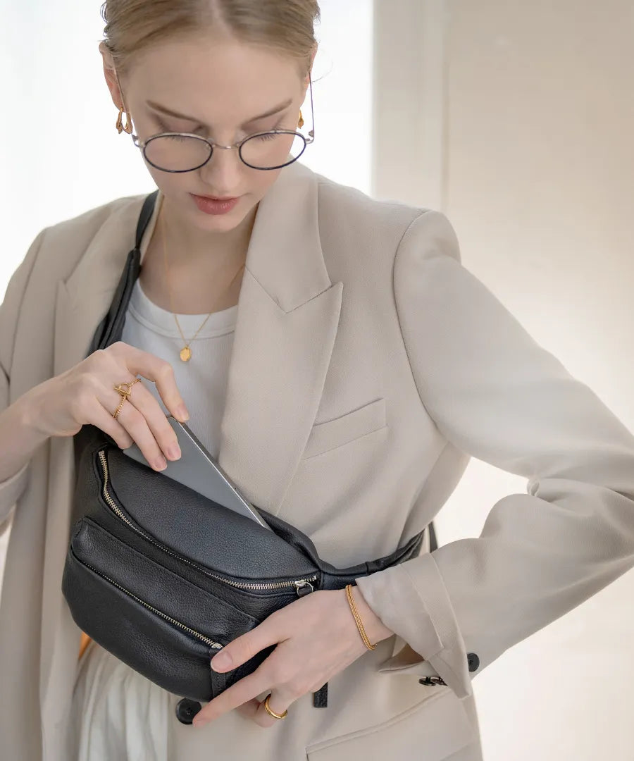 A female model wears a TIDEWAY body bag across the body. Color: black