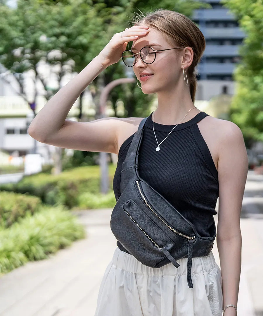 A female model wears a TIDEWAY body bag across the body. Color: black