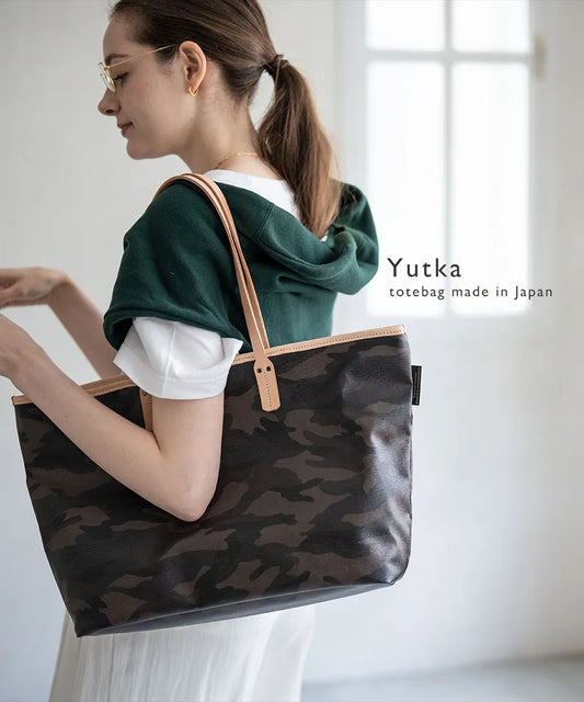 A female model is holding a tote bag "Yutka L".Color:Camouflage